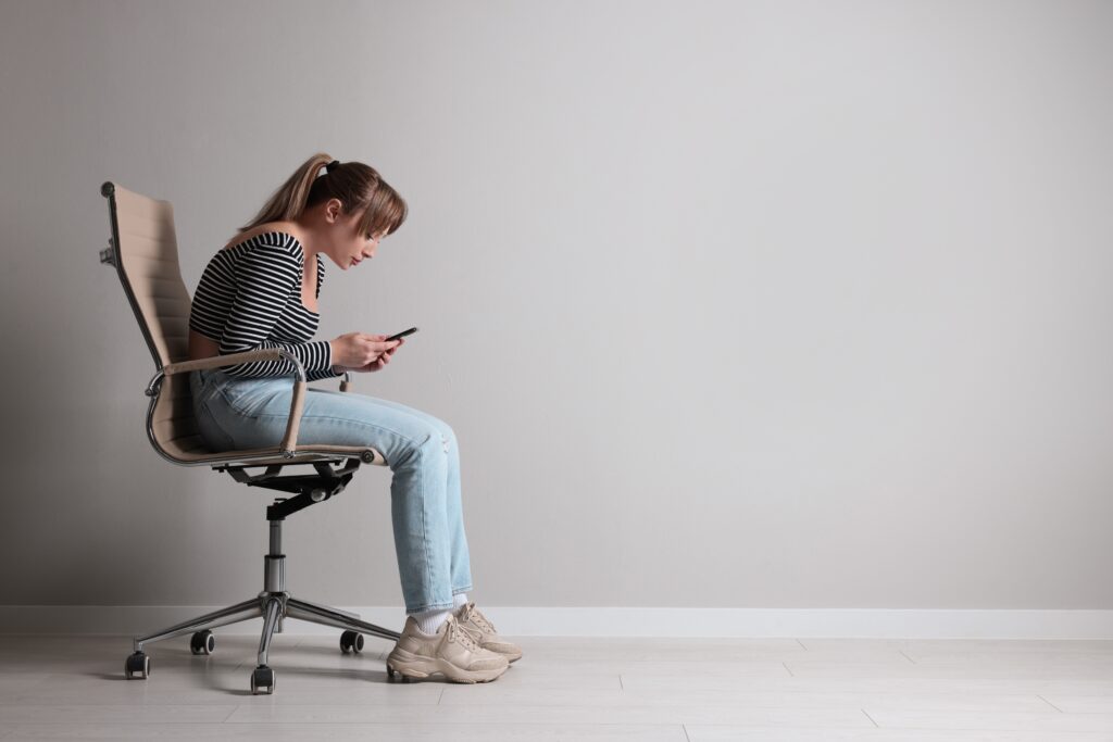 young,woman,with,poor,posture,using,smartphone,while,sitting,on