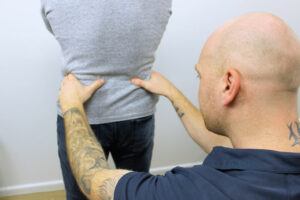 Practitioner assessing patients lower back for disc bulge