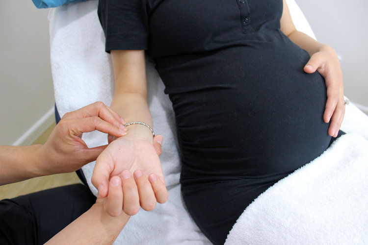 practitioner taking the pulse of a pregnant woman