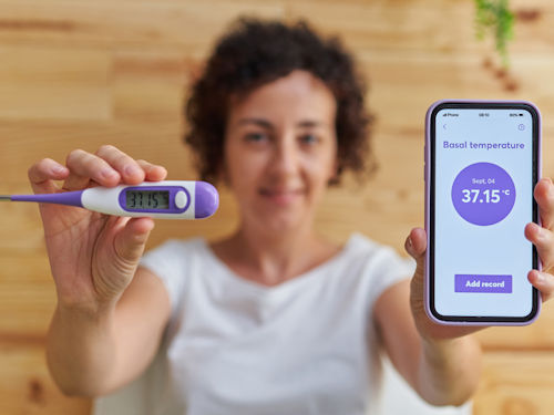 Woman recording her basal body temperature to identify and track ovulation
