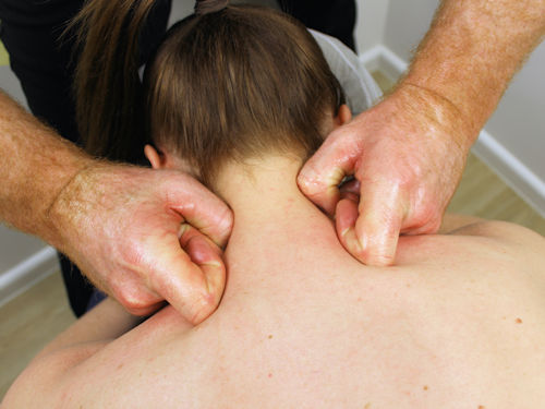 Patient having trigger point therapy to release muscle tightness to improve neck and back pain and posture