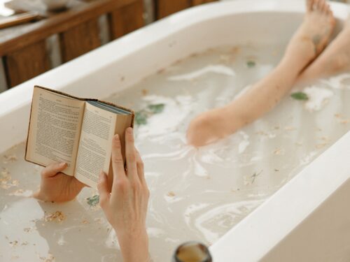 lady reading and taking a bath to destress and decompress to lower pain and help promote better sleep